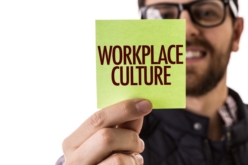 Image of man holding up a sticky note that says "Workplace Culture"