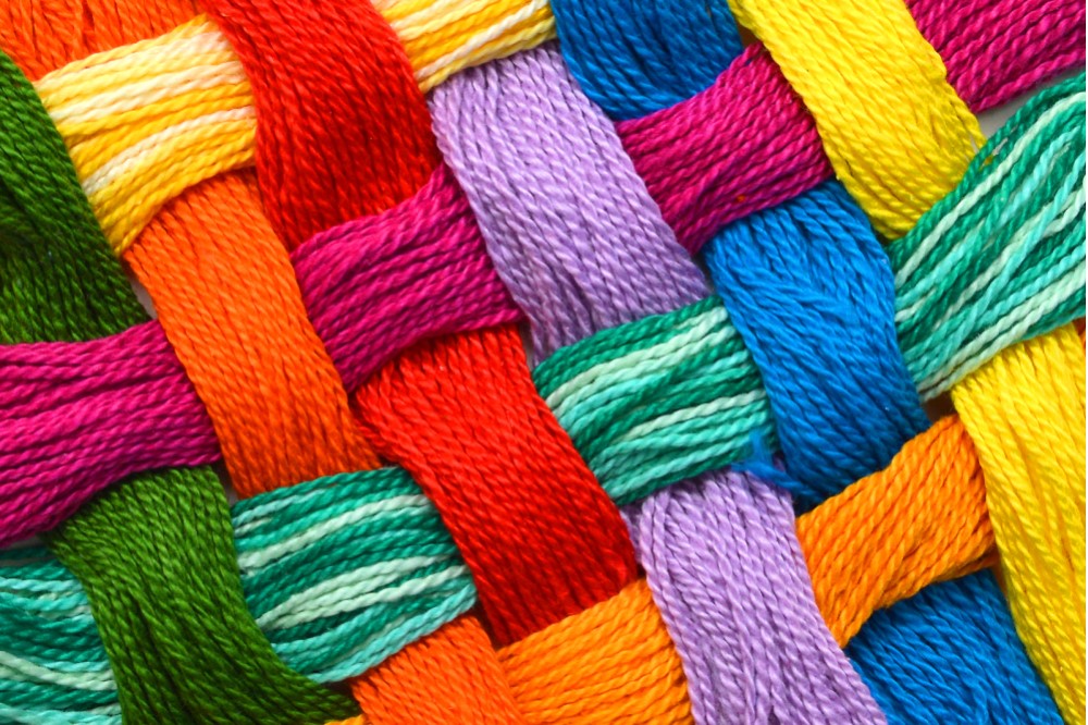 Image of various color threads woven together symbolizing the community fabric