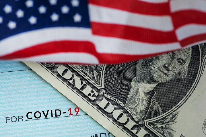 Image of American flag, US one dollar bill, check made out to COVID-19