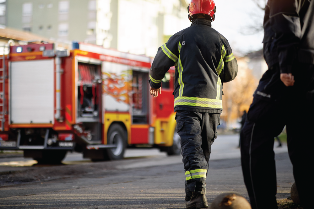 Fire fighters approaching fire truck in front of burning building