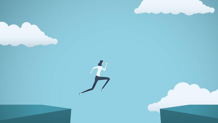 Image of business person jumping from one cliff to another