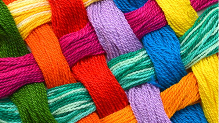 Image of various color threads woven together symbolizing the community fabric