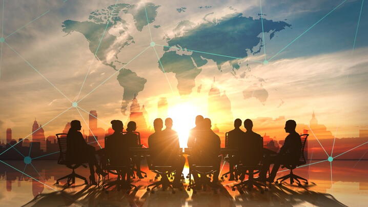 Image of C-suite with map of the world superimposed above them