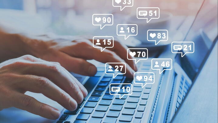 Image of a person typing on a laptop with social media like counts above