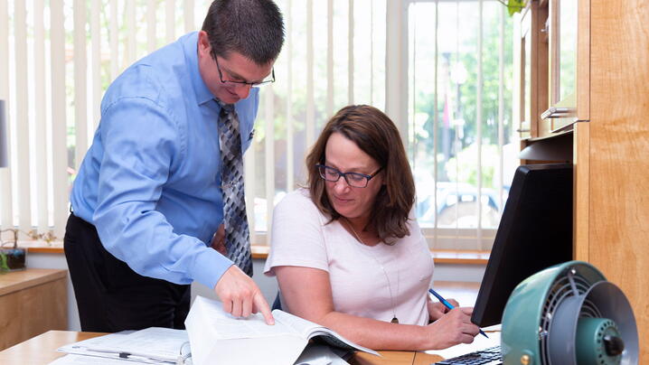 Photo of two people in an office looking at a document