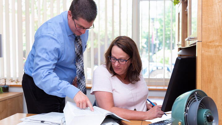 Photo of two people in an office looking at a document