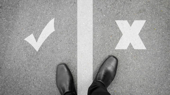 Image of person standing on a line between a check mark and an X