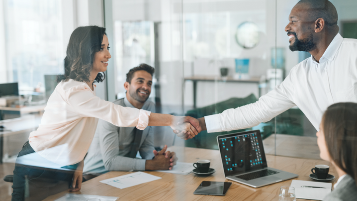 Smiling diverse businesspeople shaking hands together during a meeting