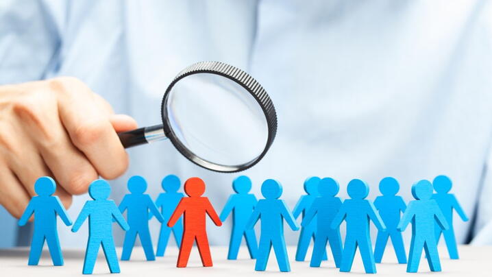 Businesspeople cutouts under magnifying glass