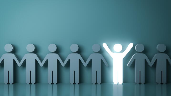 One glowing light man standing with arms wide open among other people on dark green background like 1