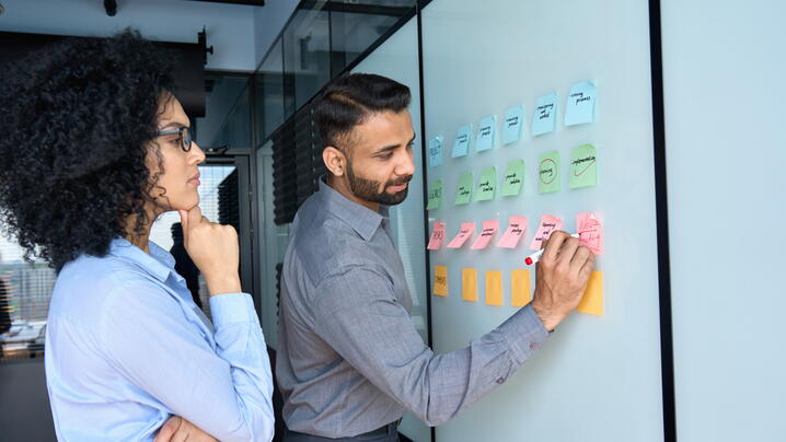 Two-multiracial-colleagues-standing-with-sticky