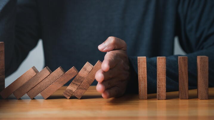Image of person's hand stopping blocks from falling
