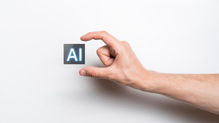 Image of fingers holding a small block that says "AI"