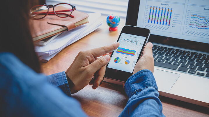 Women holding phone with graphs and charts on screen