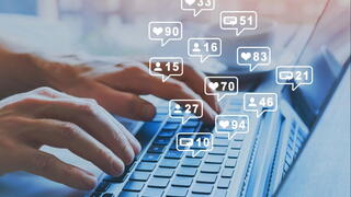 Image of a person typing on a laptop with social media like counts above