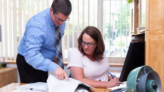 Photo of two people in an office looking at a document