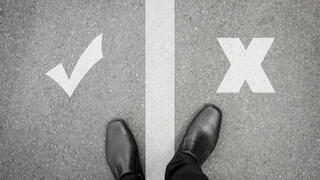 Image of person standing on a line between a check mark and an X