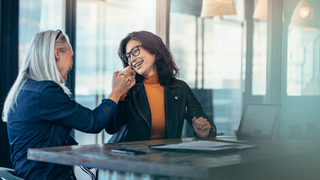 Photo of two women colleagues high-fiving