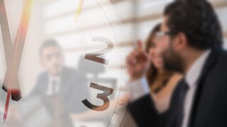 Image of a clock superimposed on a photo of folks in a meeting