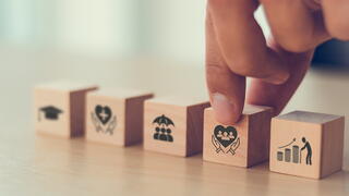 Fingers picking up a block with an image of hands holding up a heart.