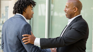 Mature African American businessman shaking hands with younger business man